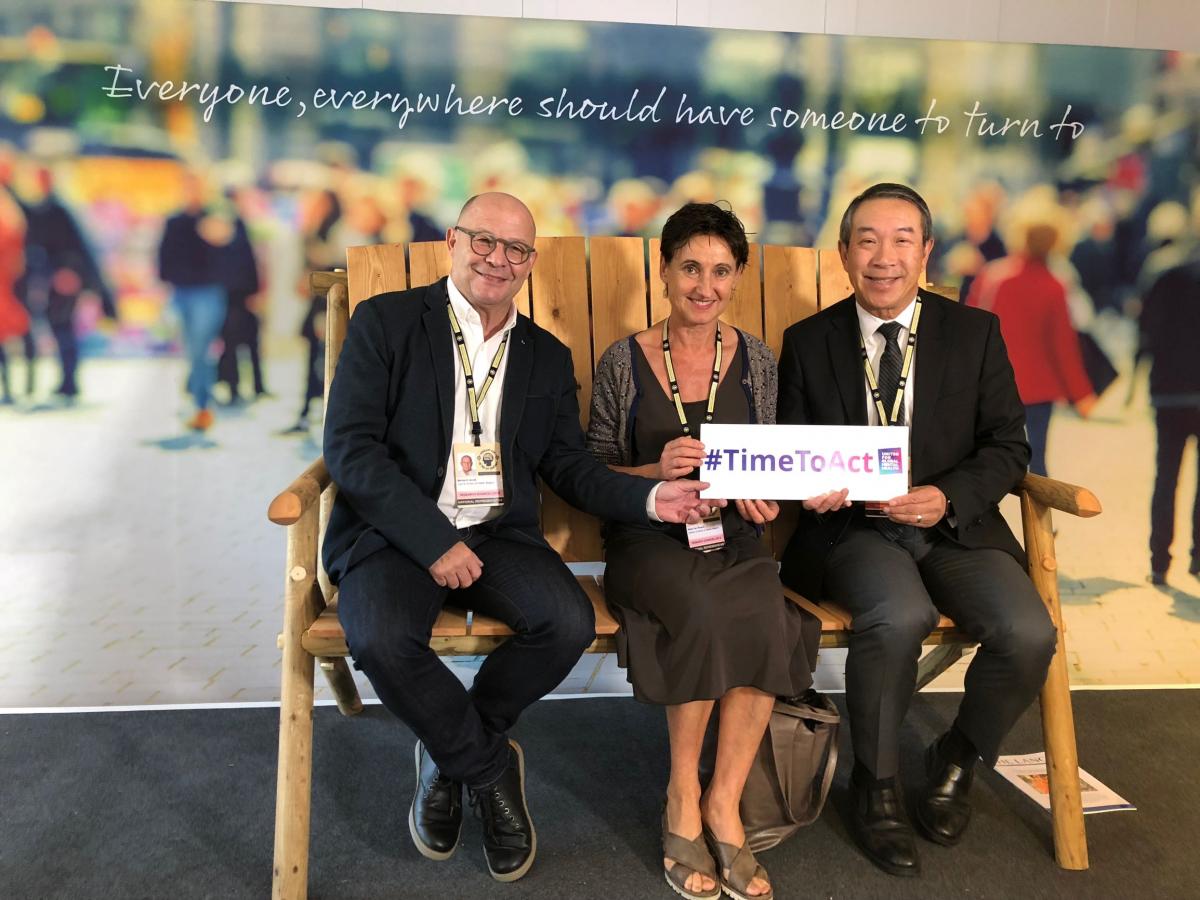 Dr. Raymond Lam (L) and colleagues from the Belgian Ministry of Health sit on the "Friendship Bench", London, 9 Oct. 2018